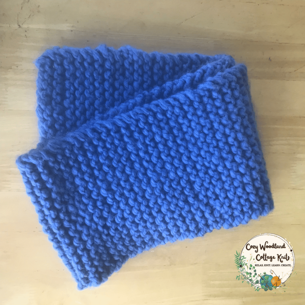 a blue hand knitted chunky scarf folded up.