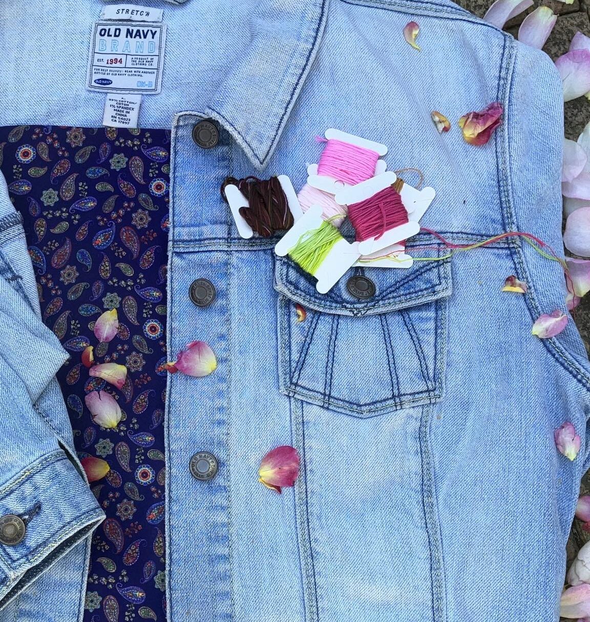 a light blue denim jacket with spools of brightly coloured embroidery thread