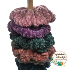 A wooden scrunchies holder with seven scrunchies on it.