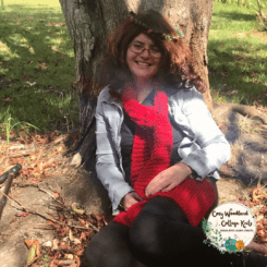 A photo of Arjaye-Rose sitting under a tree wearing a red Autumn Leaves Chunky Scarf.