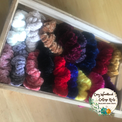 A photo of a wooden crate filled with scrunchies in different colours.